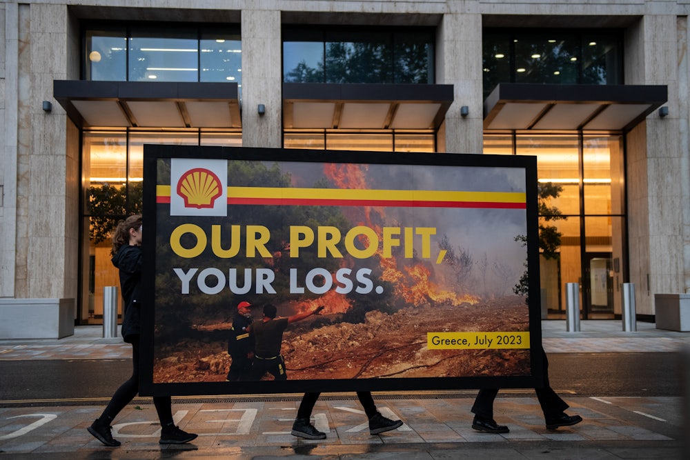 Greenpeace activists hold a billboard during a protest outside Shell headquarters