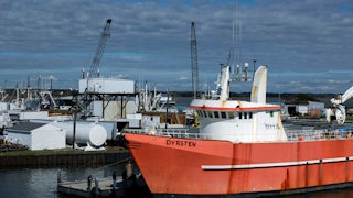 A red fishing boat is seen at a dock.