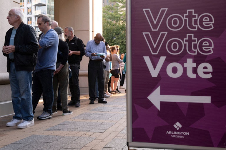 People stand next to a sign reading "Vote Vote Vote."