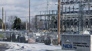 Massive spools of wires, as well as the steel towers of substation, sit behind a chain-link fence, with a sign reading "NES Donelson Center 219 Stewarts Ferry Pike."