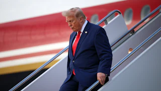 Donald Trump purses his lips and looks down while walking down the steps of Air Force One.
