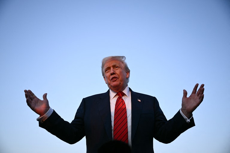 Donald Trump holds his arms up while speaking to reporters