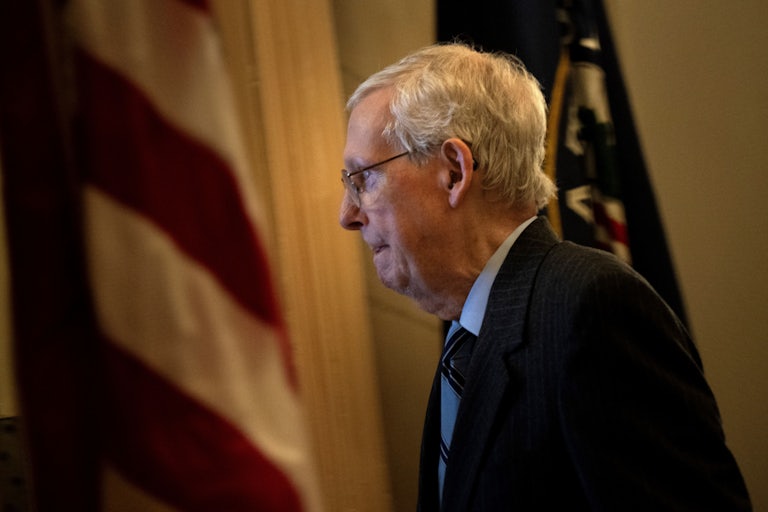 Mitch McConnell stands in profile next to an American flag