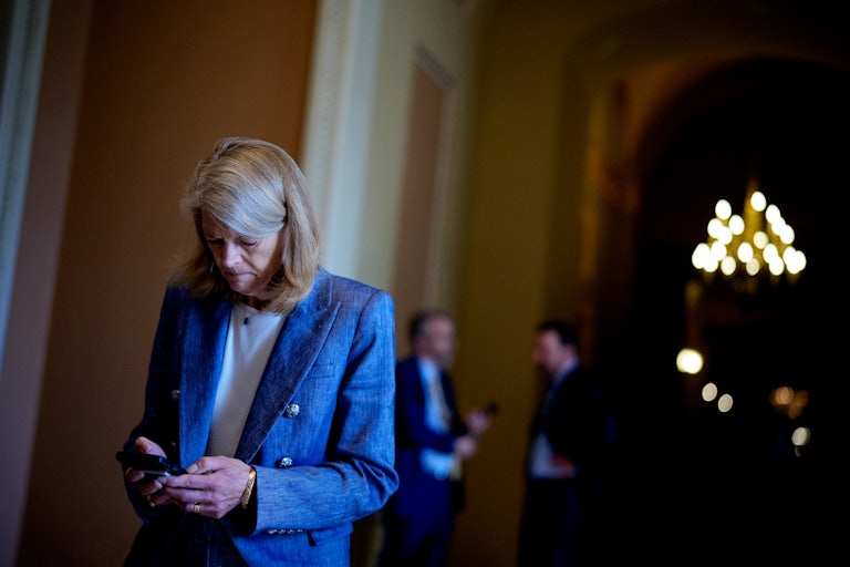 Senator Lisa Murkowski looks down at her phone while walking in the Capitol