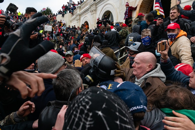 A very large crowd of men surround a Metropolitan Police officer near the Capitol on January 6, 2021.