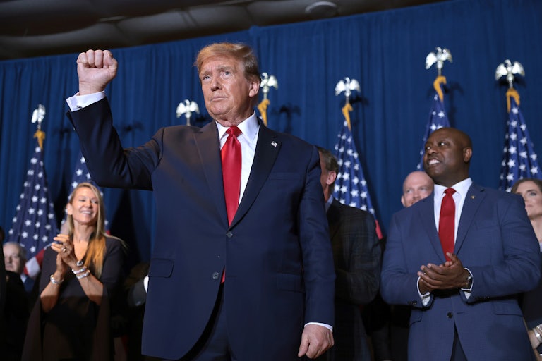 Donald Trump stands while holding his fist in the air