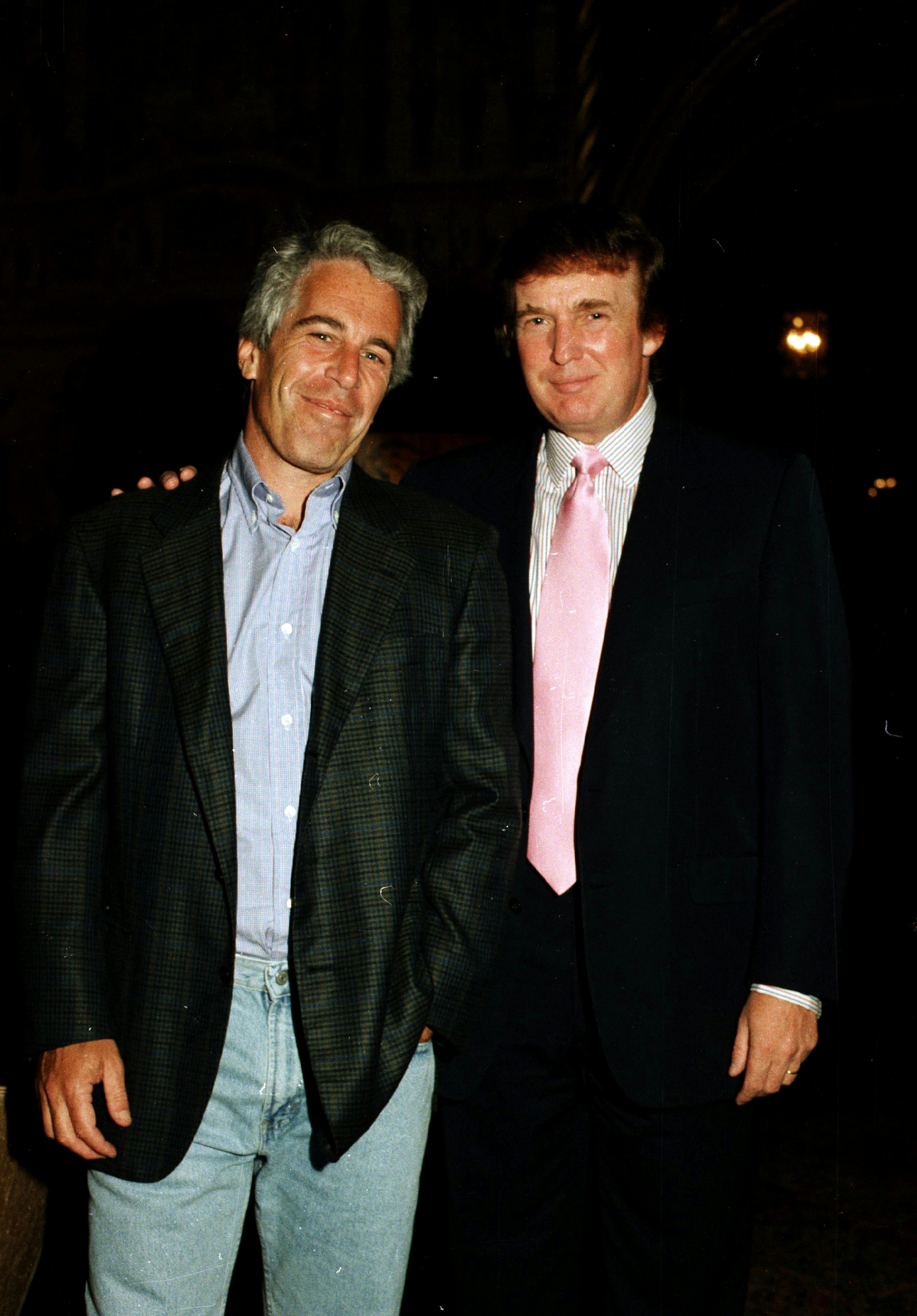 Jeffrey Epstein and Donald Trump smile while standing next to one another. Trump places his hand on Epstein's shoulder.