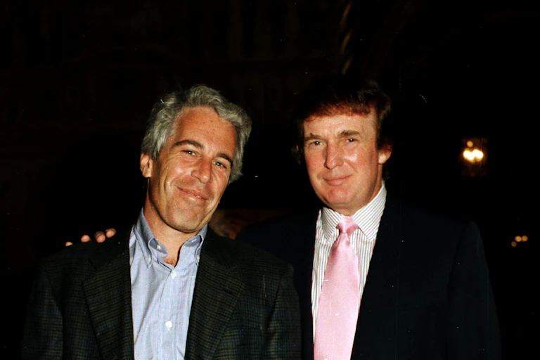 Jeffrey Epstein and Donald Trump smile while standing next to one another. Trump places his hand on Epstein's shoulder.