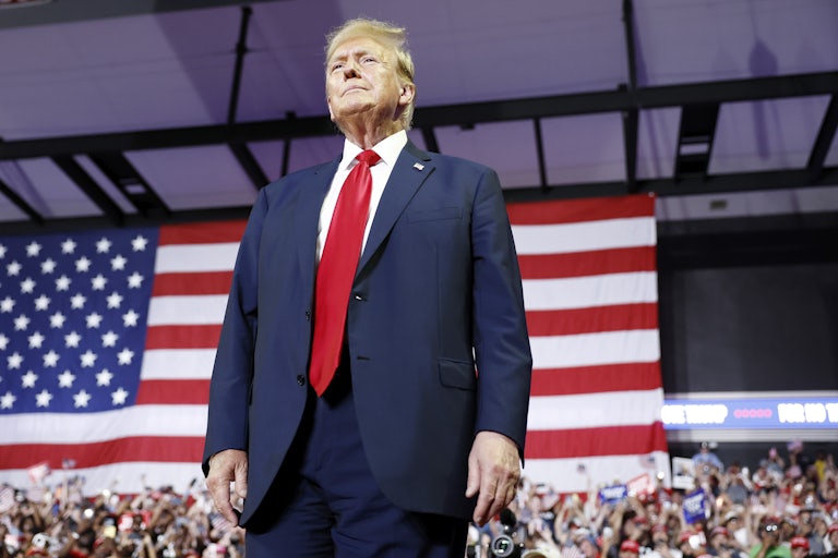 Donald Trump stands in front of a large U.S. flag.