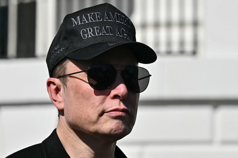 Elon Musk wears a black "Make America Great Again" hat and aviator sunglasses while standing outside the White House