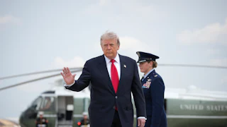 President Donald Trump waves as he leaves Marine One (in the background)