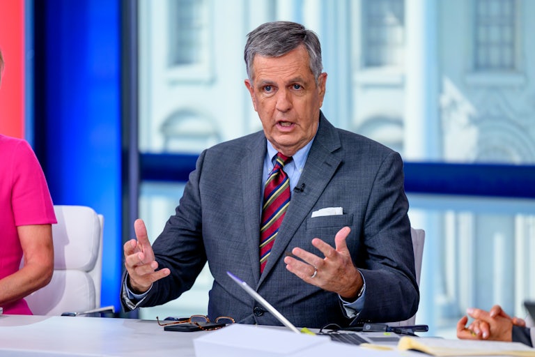 Brit Hume gestures while sitting at a desk