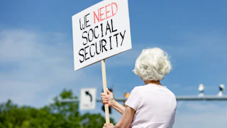Lynn McKerral holds a sign in support of Social Security Administration workers in front of the agency’s headquarters.