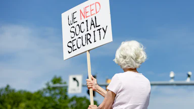 Lynn McKerral holds a sign in support of Social Security Administration workers in front of the agency’s headquarters.