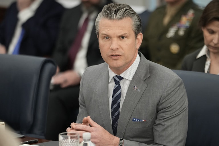 Pete Hegseth sits at a table and speaks