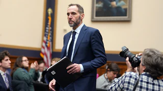 Jack Smith holds a folder while in a congressional hearing