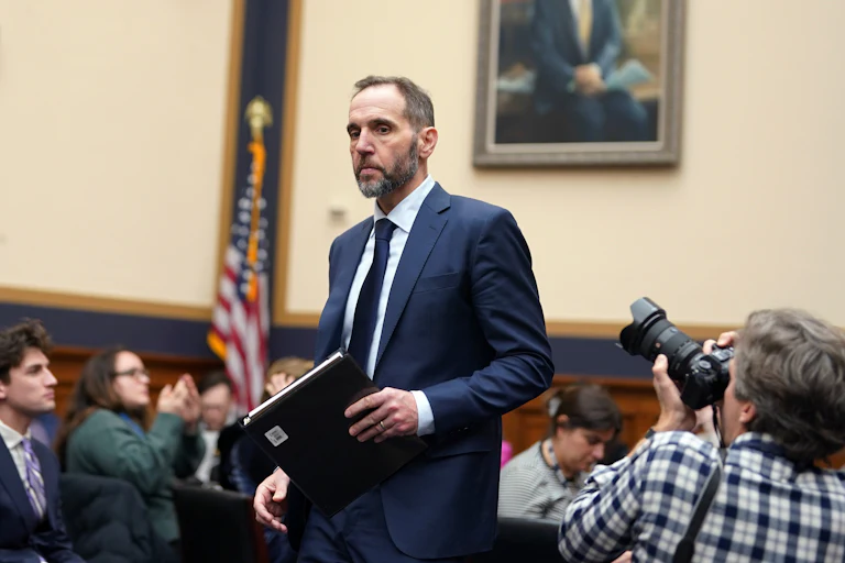 Jack Smith holds a folder while in a congressional hearing