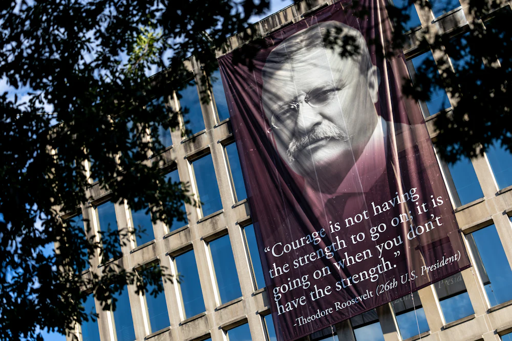 A banner that reads, “Courage is not having the strength to go on; it is going on when you don’t have the strength,” with a photo of the 26th U.S. president Theodore Roosevelt, is hung outside the Theodore Roosevelt Federal Building in Washington, D.C. The quote’s origin can be traced back to multiple different people but attributed to President Roosevelt on the banner.