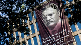 A banner that reads, “Courage is not having the strength to go on; it is going on when you don’t have the strength,” with a photo of the 26th U.S. president Theodore Roosevelt, is hung outside the Theodore Roosevelt Federal Building in Washington, D.C. The quote’s origin can be traced back to multiple different people but attributed to President Roosevelt on the banner.