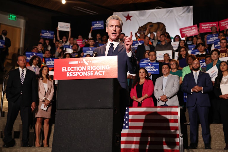 CA Governor Gavin Newsom stands in front of a crowd at a podium.