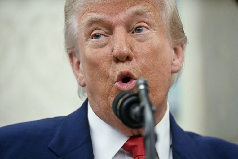Donald Trump speaks into a microphone in the Oval Office