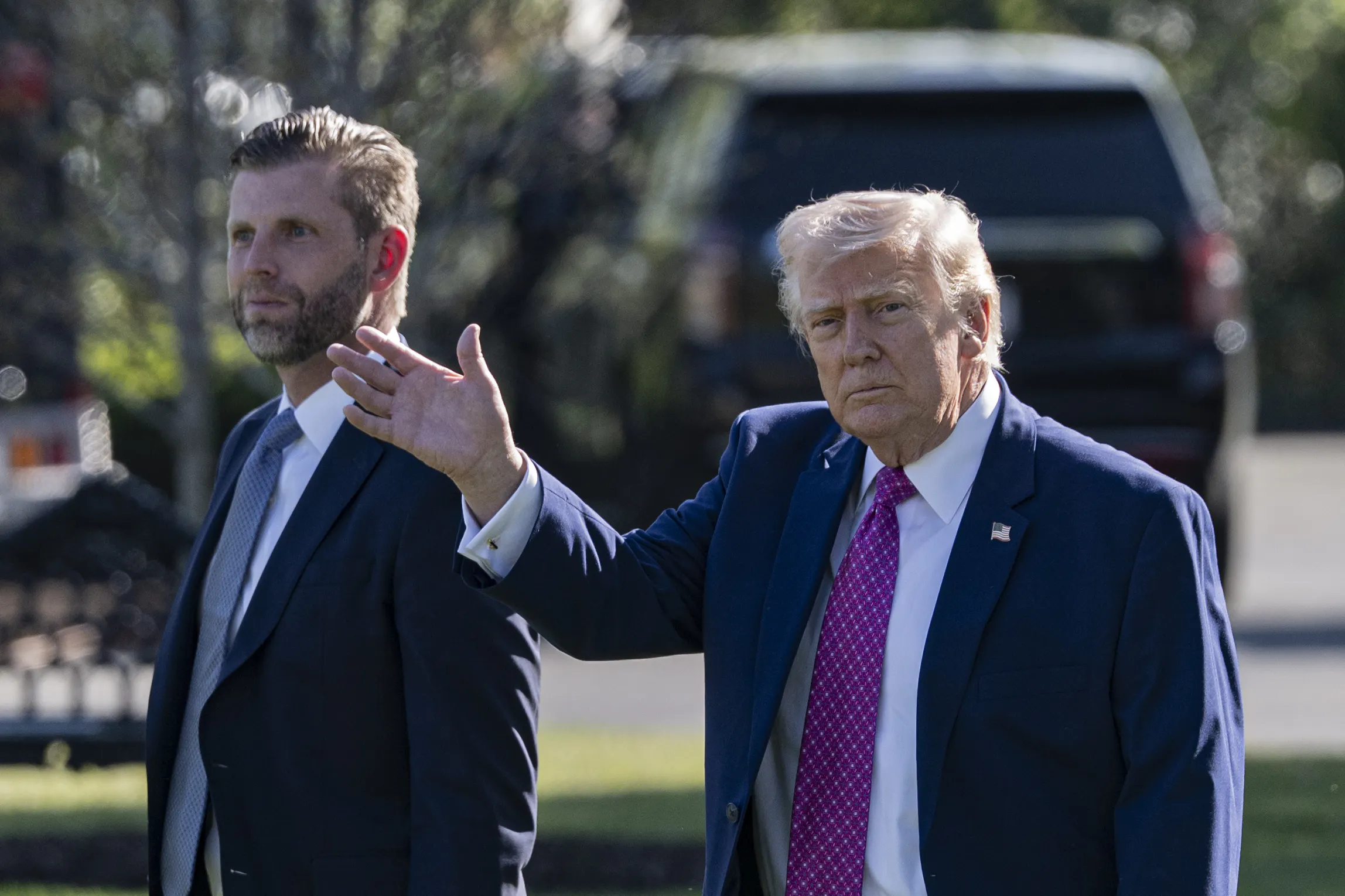 Donald Trump waves while walking next to his son Eric Trump outside the White House