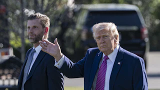 Donald Trump waves while walking next to his son Eric Trump outside the White House