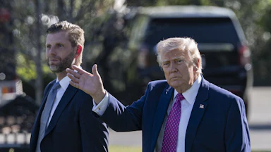 Donald Trump waves while walking next to his son Eric Trump outside the White House