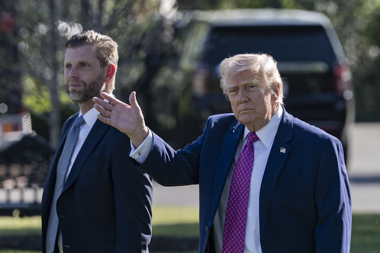 Donald Trump waves while walking next to his son Eric Trump outside the White House