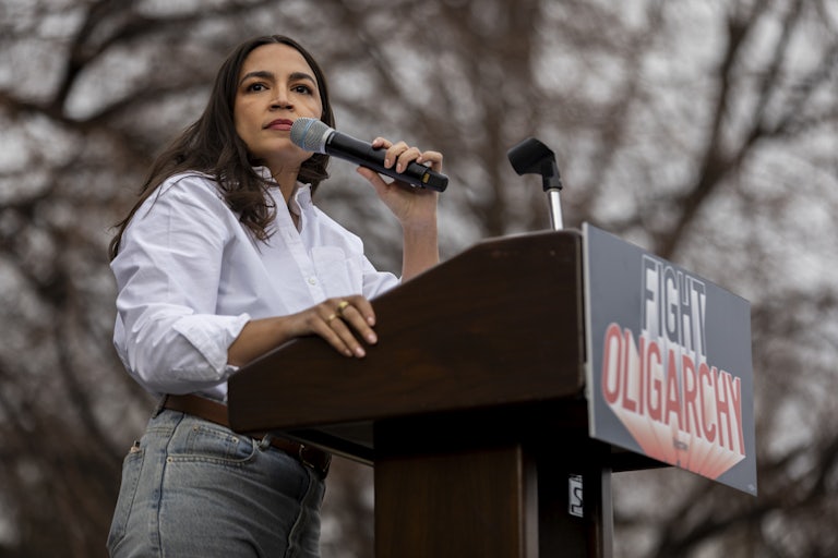 Representative Alexandria Ocasio-Cortez speaks at a lectern that reads "Fight Oligarchy."