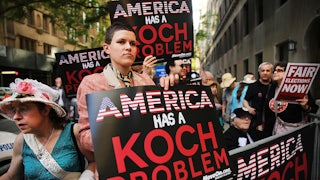 Protesters hold signs that read "America has a Koch problem"