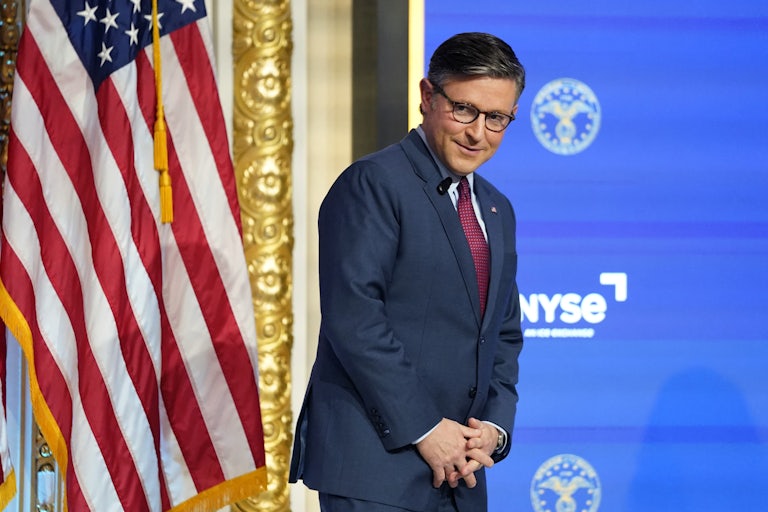 Mike Johnson leans forward slightly with his hands folded in front of him