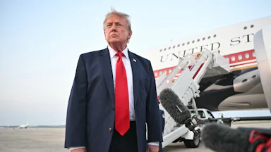 Donald Trump stands in front of reporters next to Air Force One