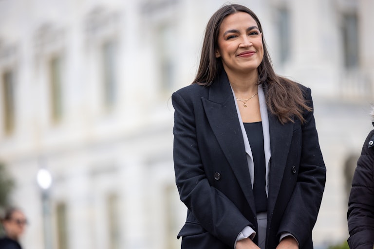 Representative Alexandria Ocasio-Cortez smiles while standing outside Congress
