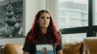 A portrait of Misty Leon holding a photograph of her mother, sitting on a couch in an apartment in Vancouver, Canada.