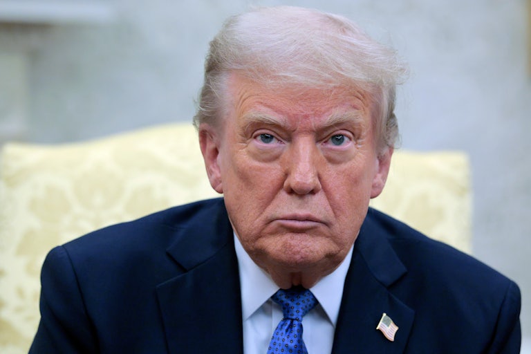 Donald Trump stares blankly ahead while sitting in the Oval Office
