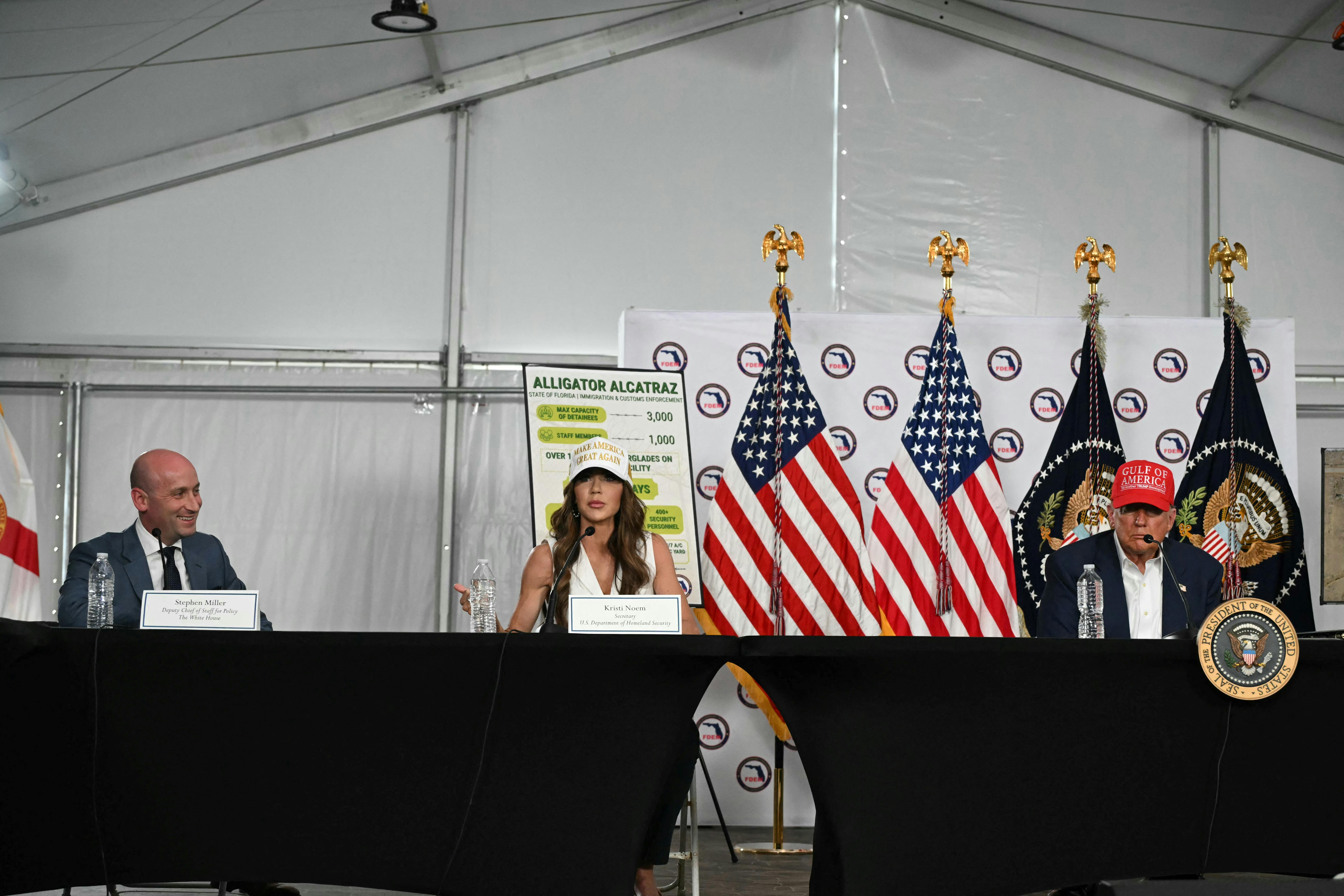 Homeland security secretary Kristi Noem, flanked by Donald Trump and White House deputy chief of staff Stephen Miller, spoke on July 1 during a roundtable discussion at a migrant detention center in Florida dubbed “Alligator Alcatraz.” 