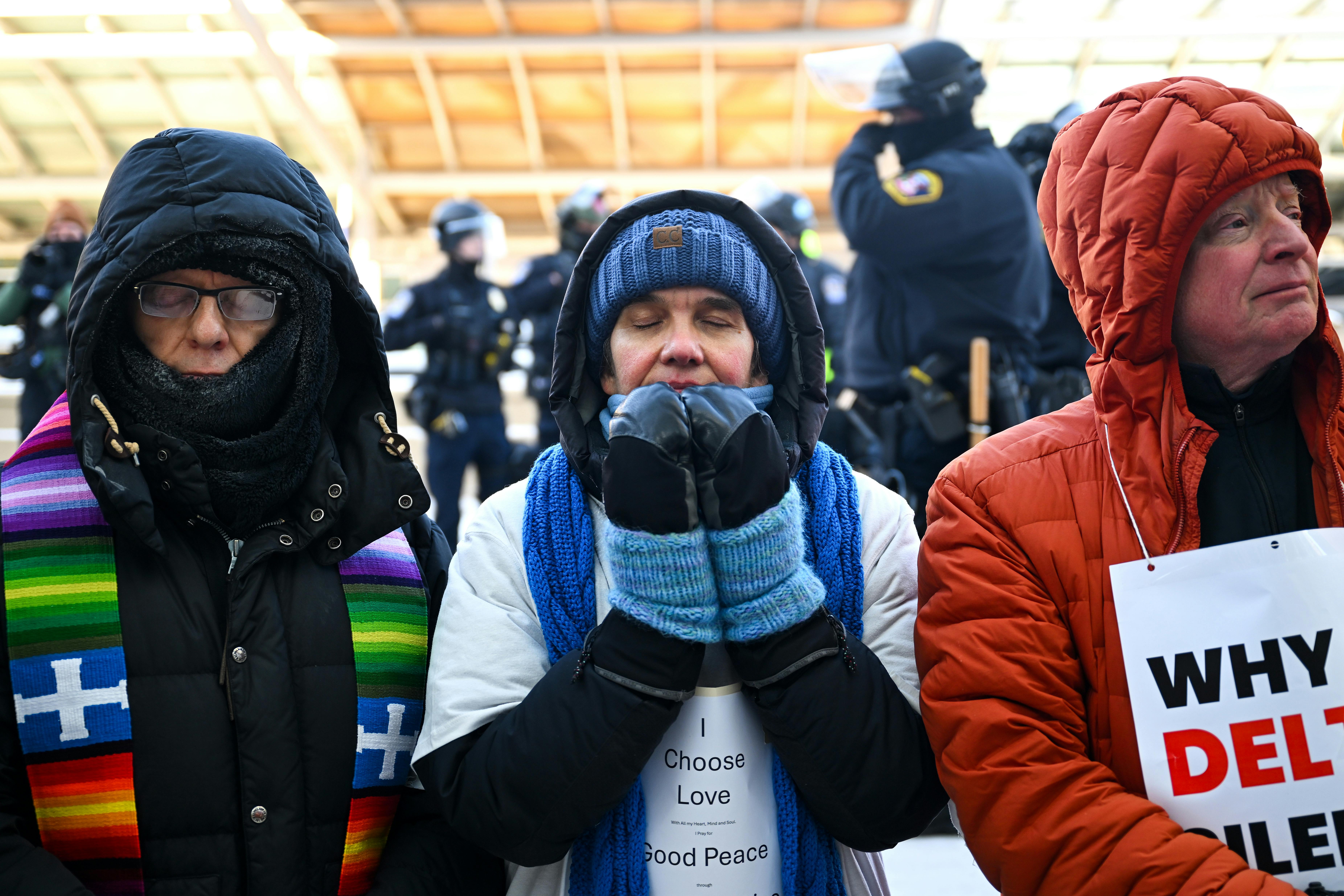 Faith leaders pray during a protest at the Minneapolis airport