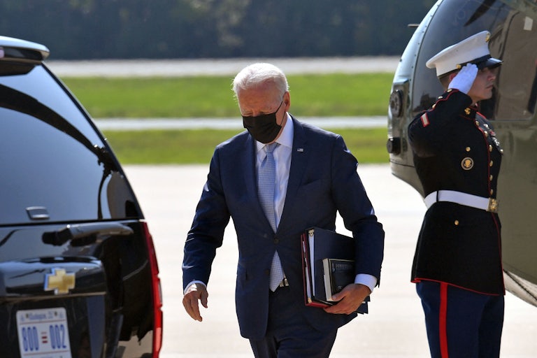 President Biden carries folders away from Marine One.