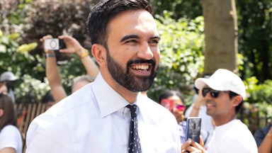 New York City mayoral candidate Zohran Mamdani is seen at the 2025 NYC Pride March on June 29, 2025 in New York, New York. He is wearing a white button-up shirt and a spotted black tie and smiling.