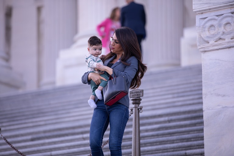 Representative Lauren Boebert walks down the Capitol steps holding her baby grandson.