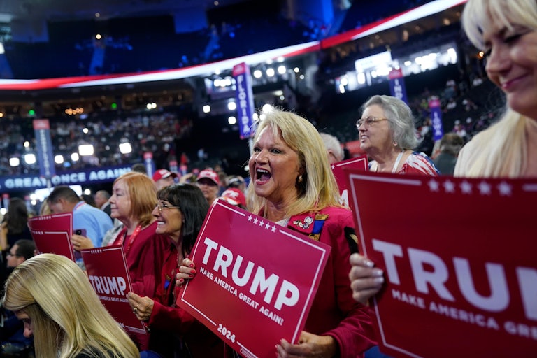 Delegates smile and hold "Trump" campaign signs during the RNC. (They're all old white women in this shot.)