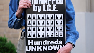 A person holds a sign that says, "Kidnapped by ICE. Hundreds unknown" at a rally protesting against Donald Trump's deportations