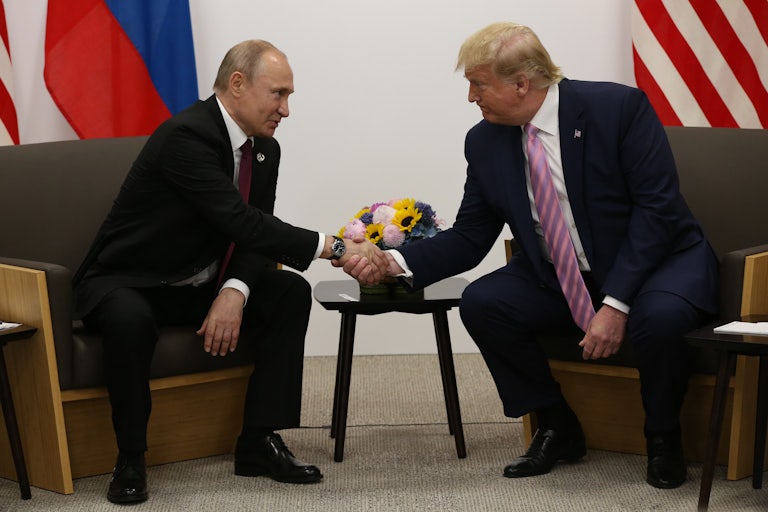 Donald Trump shakes hands with Russian leader Vladimir Putin