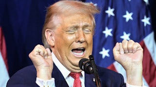 Donald Trump holds up his fists while speaking into a microphone