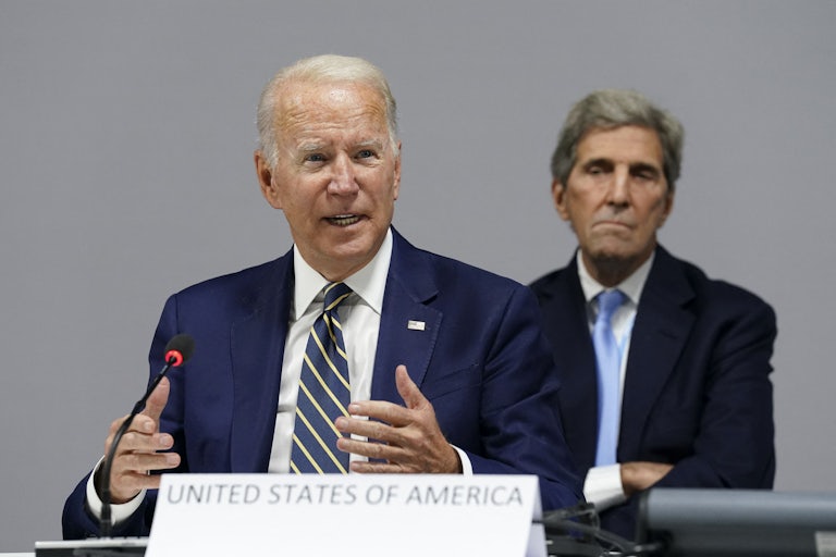 Joe Biden speaks at COP26, with John Kerry in the background.