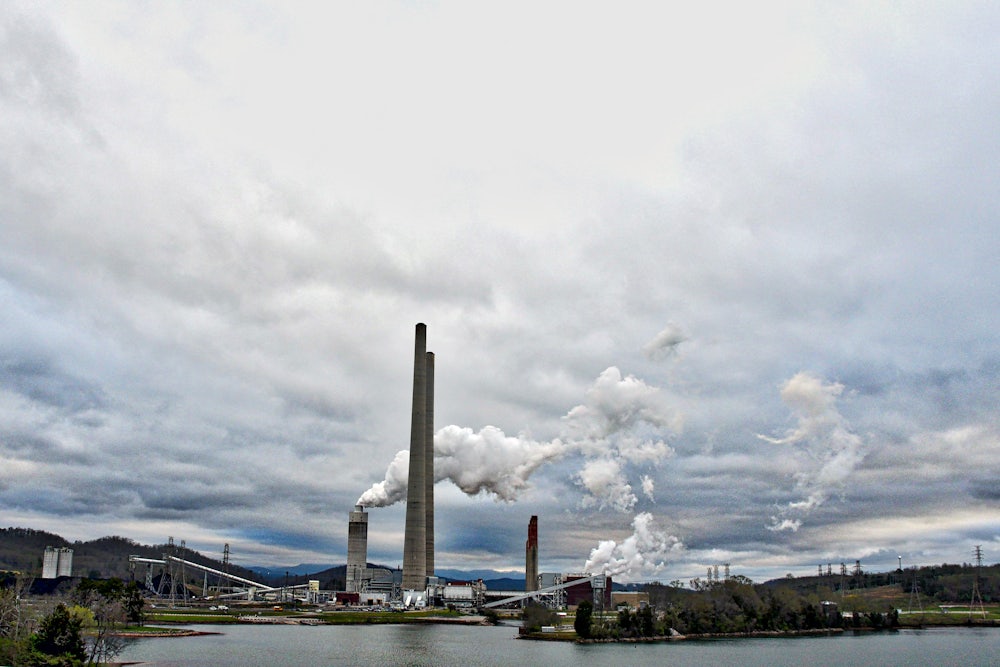 Steam rises from towers on the edge of a lake.