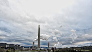 Steam rises from towers on the edge of a lake.
