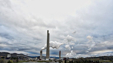 Steam rises from towers on the edge of a lake.
