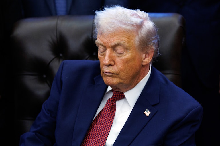 Donald Trump looks down while sitting at his desk in the Oval Office